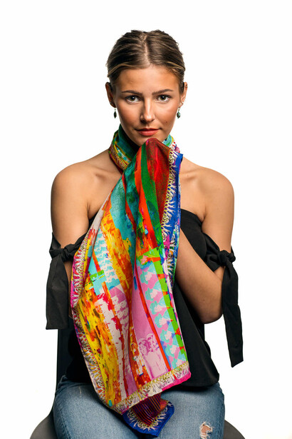 Woman wearing colorful patterned scarf and black off-shoulder sleeves against white background.