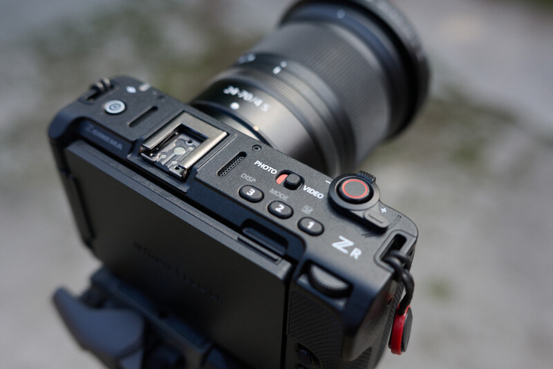 Top-down view of a compact mirrorless camera with attached lens and red recording indicator light.