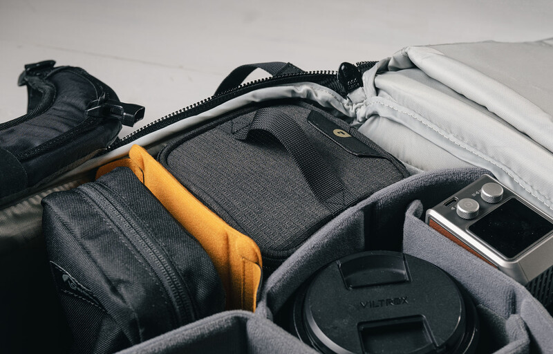 Camera bag interior with organized compartments holding a camera lens, smartphone, and various accessories.