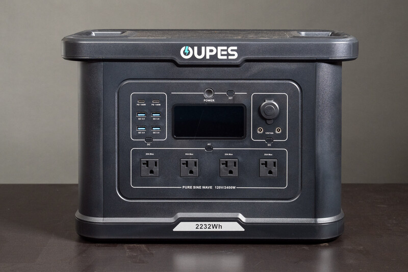 OUPES portable power station with digital display and four AC outlets on dark wooden surface.