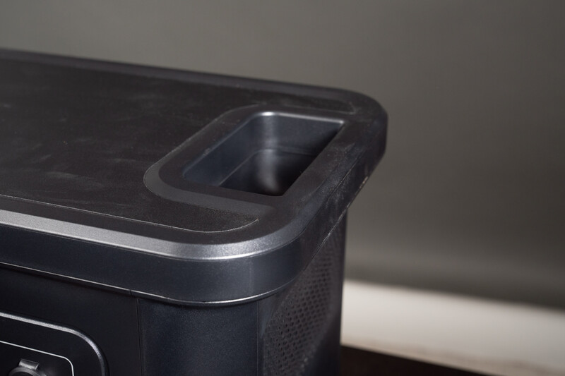 Close-up of a black device with rounded edges and a rectangular recessed slot on top surface.