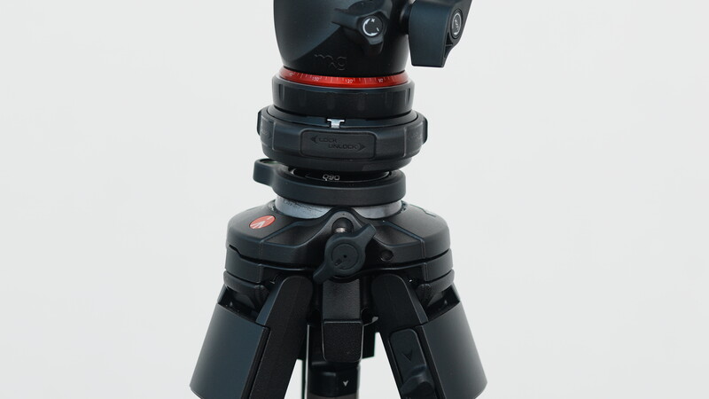 Professional tripod head with red band and pan-tilt controls mounted on dark tripod legs.