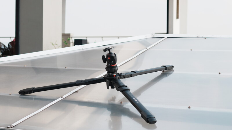 Helicopter rotor head and blades mounted on white surface with industrial building in background.