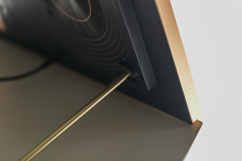 Close-up of a camera lens with gold trim against a neutral background.