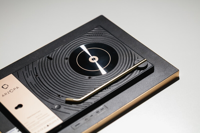 Overhead view of a turntable with concentric vinyl record grooves and tonearm against a minimalist flat lay setup.