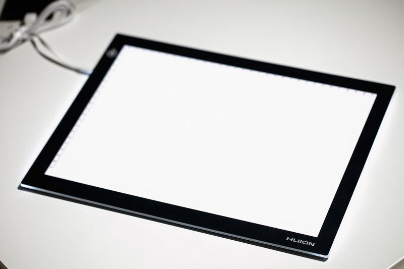 Huion graphics tablet with black frame and white surface on neutral background.