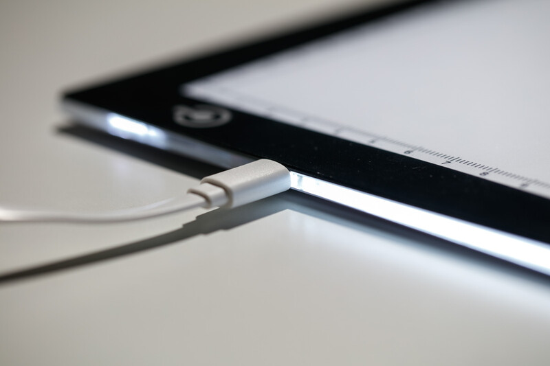 Close-up of a white charging cable connected to the port of a tablet device.
