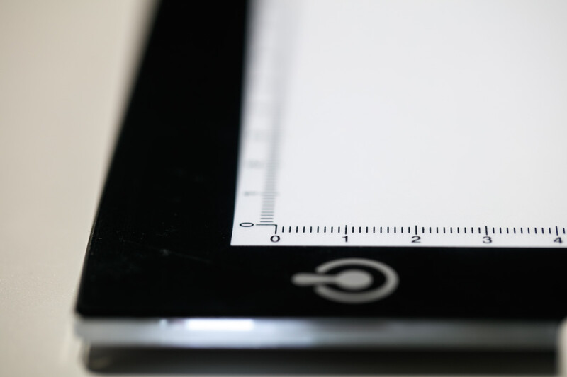 Close-up of a ruler placed on the edge of a black tablet or device with a measurement scale visible.