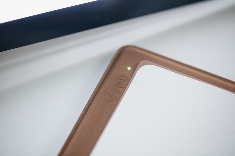 Close-up of a brown picture frame corner showing the frame edge and white mat opening against a white background.