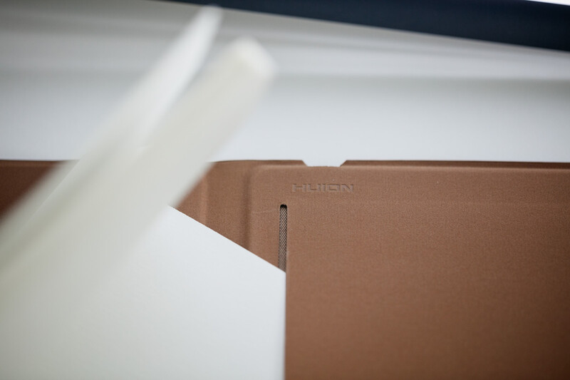 Close-up of a cardboard box flap with a metal fastener and white tissue paper visible above it.