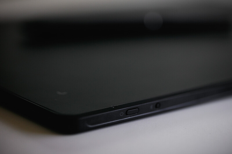 Close-up of a black smartphone's edge showing the power button and frame detail against a light surface.