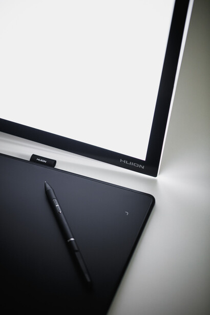 Overhead view of a blank tablet with stylus and open laptop on white desk surface.