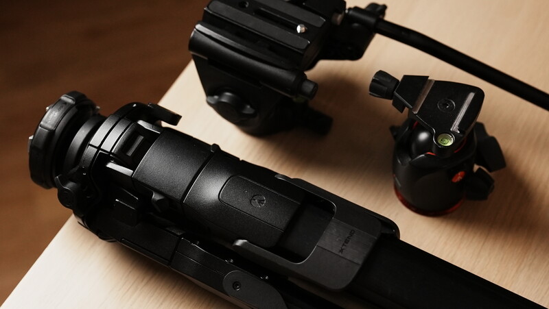 Three black camera support accessories arranged on a light wood surface.