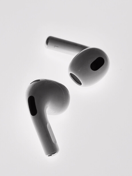 Two wireless earbuds photographed against a white background with dramatic side lighting.