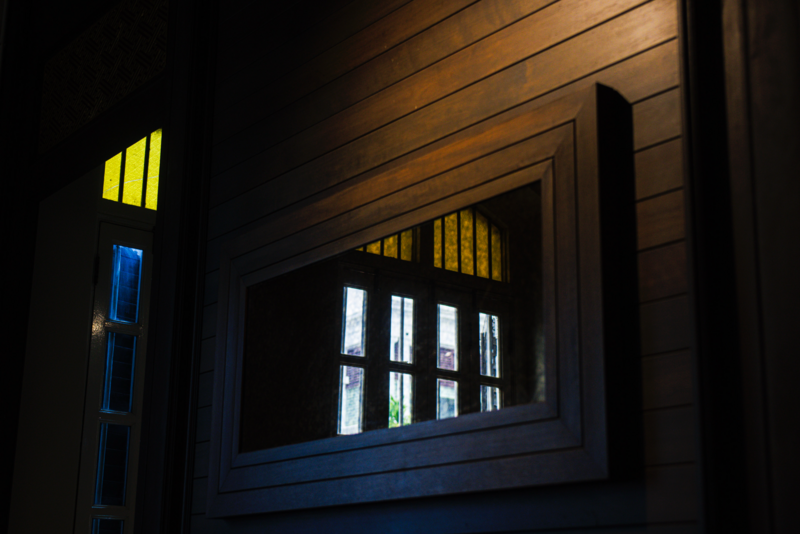 Nighttime architectural shot of wooden-paneled building facade with illuminated windows casting warm and cool light against dark surroundings.