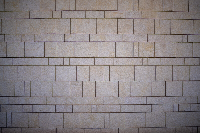 Stacked stone or concrete tiles in a running bond pattern with warm beige and gray tones.