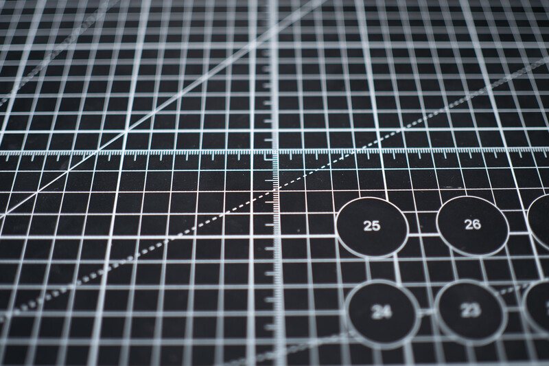 Close-up of a graph paper surface with plotted curves, measurement ruler, and numbered circular markers.