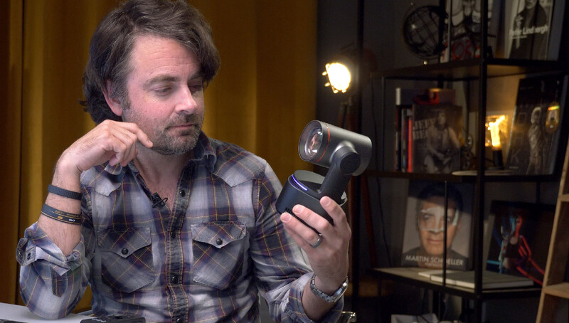 Photographer holding a compact camera while examining its display screen in a studio setting.