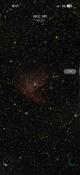 Deep-sky astrophotography showing NGC 281 nebula region with stars and dark dust clouds.