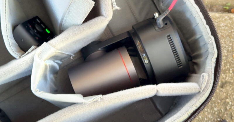 Telephoto lens and compact camera stored in padded camera bag with foam compartments.
