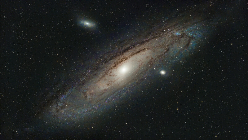 Spiral galaxy with bright central nucleus and dust lanes viewed at an angle against a starfield.