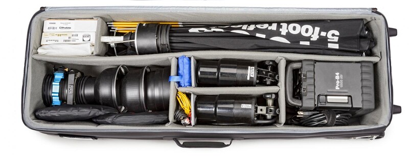 Professional video production equipment organized in a protective hard case, including cinema lens, follow focus system, wireless transmitter, and power supply.