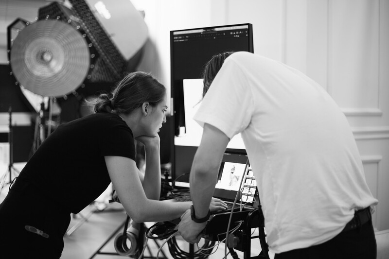 Two people reviewing footage on a monitor during a film or photography production setup.
