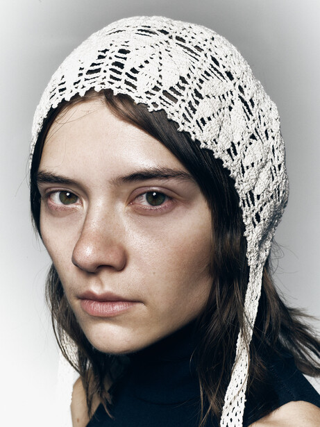 Portrait of a person wearing a white knit head wrap covering most of their dark hair.