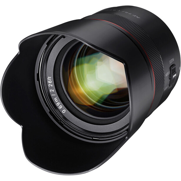 Fast telephoto lens with golden glass elements visible through the barrel and wide-angle hood attached.