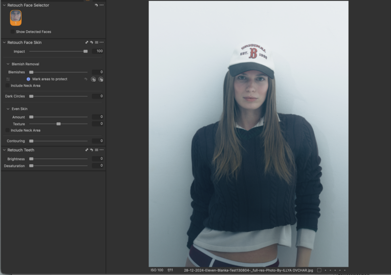 Portrait of a woman wearing a dark sweatshirt and white baseball cap against a light background.