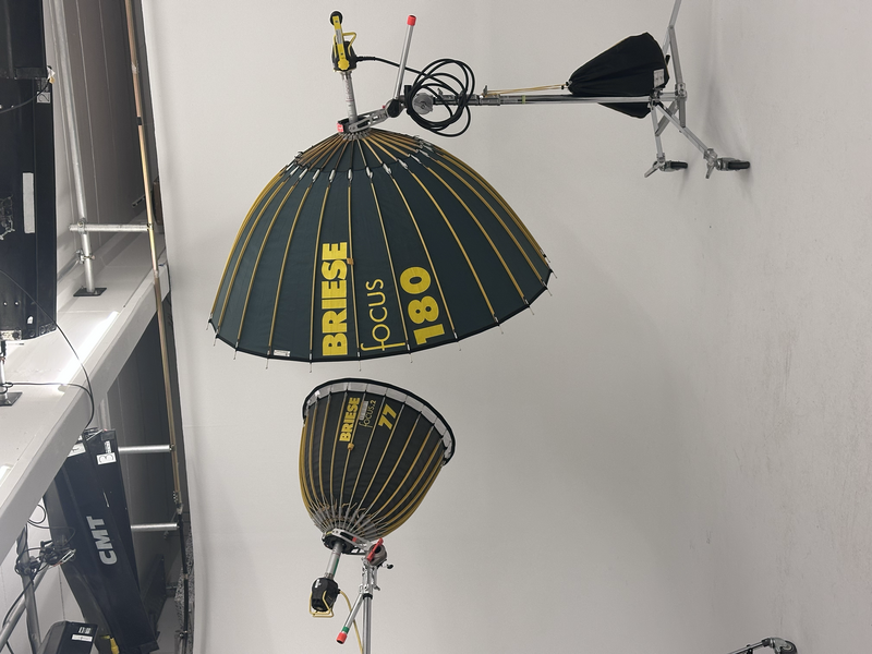 Two large black and yellow parachutes suspended from the ceiling of a white room, with rigging equipment and suspension lines visible.