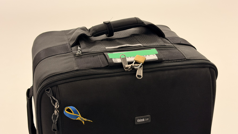 Black camera bag with organized pockets, yellow scissors keychain, and memory cards visible in top compartment.
