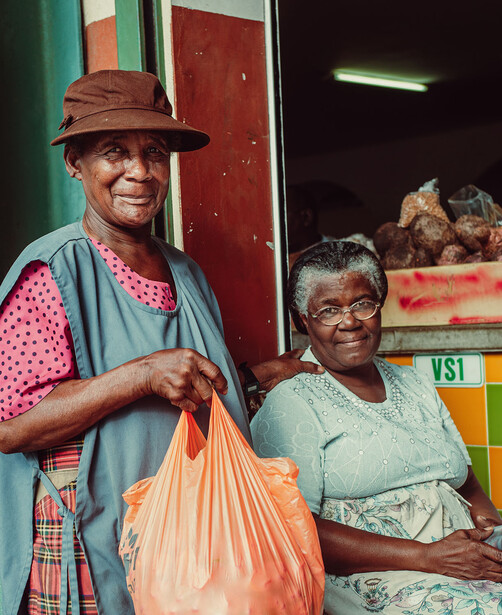 Two women smiling at a colorful storefront with vibrant green and red painted walls.