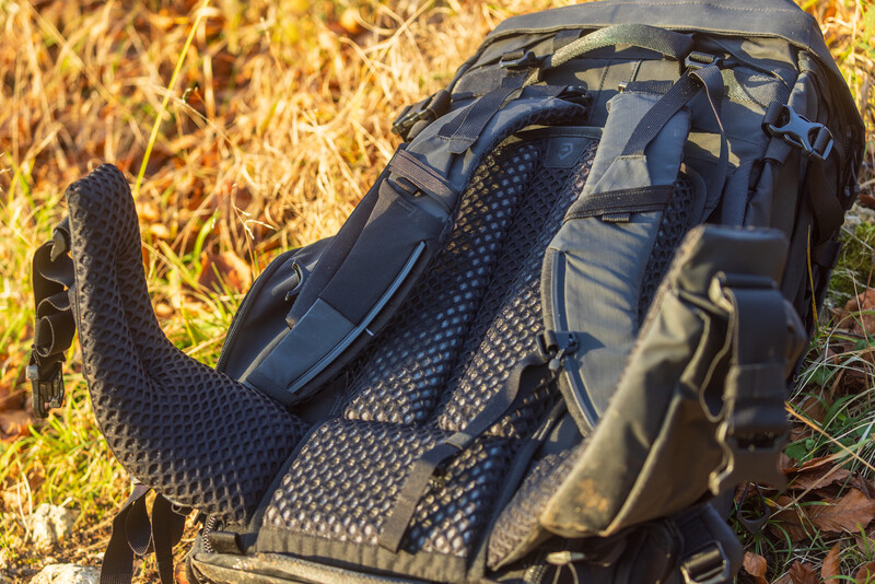 Hiking backpack with mesh ventilation panels displayed on dry grass and straw.