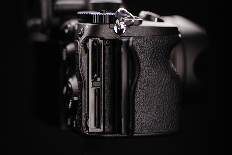 Professional DSLR camera body with textured grip and control panels against dark background.