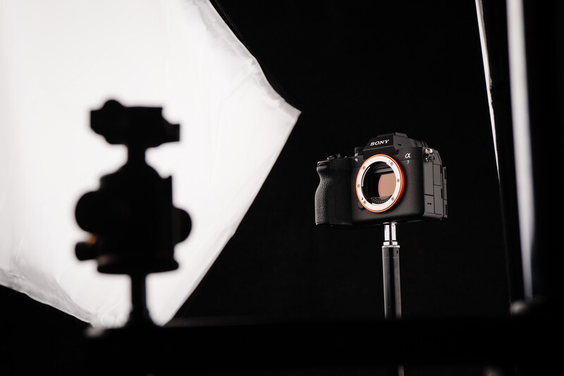 Sony mirrorless camera on tripod with silhouette of figurine projected on backlit diffusion panel.