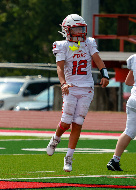 Football player in white and red uniform jogging on field during daytime.