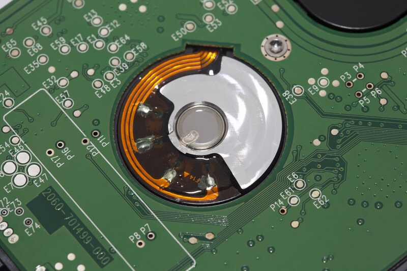 Close-up of a hard drive's internal platter and spindle motor mounted on a green circuit board.