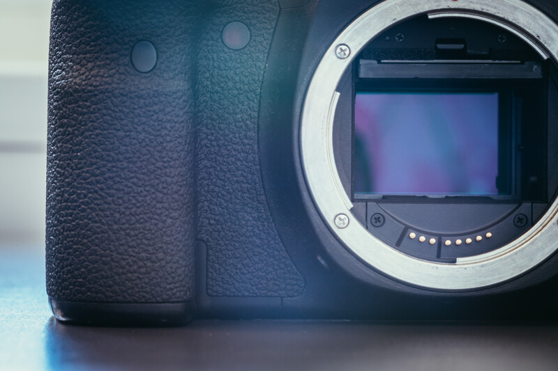 Mirrorless camera body with textured grip and exposed sensor mount assembly.