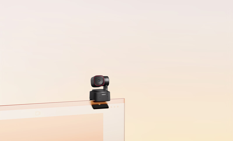 Small black PTZ camera mounted on top of a white frame against a beige background.