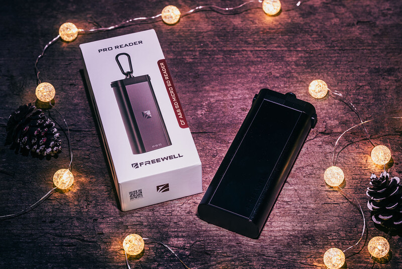 Freewell Pro Reader phone accessory with packaging and smartphone displayed on textured surface surrounded by warm string lights.