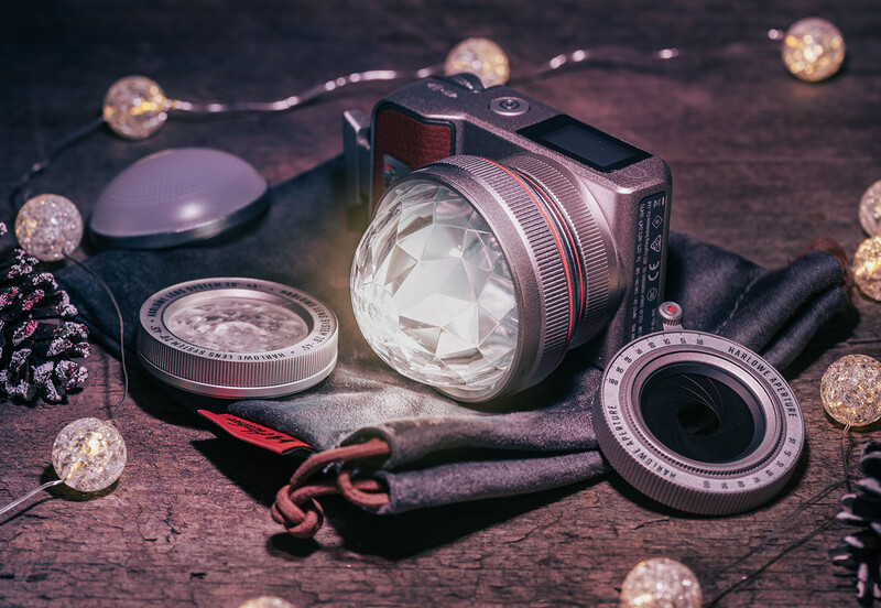 Vintage camera lenses and photography accessories arranged on a wooden surface with warm bokeh lighting.