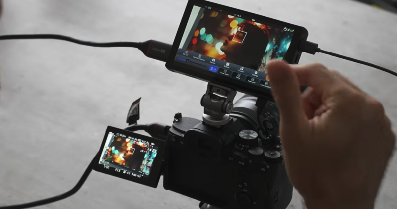 Filmmaker monitoring dual external displays connected to a cinema camera during production.