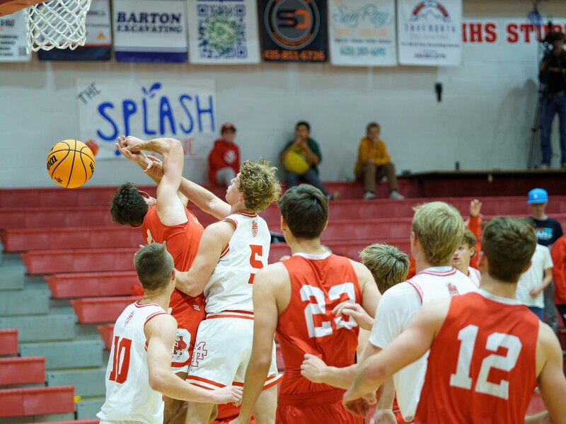 Young basketball players jumping for the ball during a game in an indoor gymnasium.