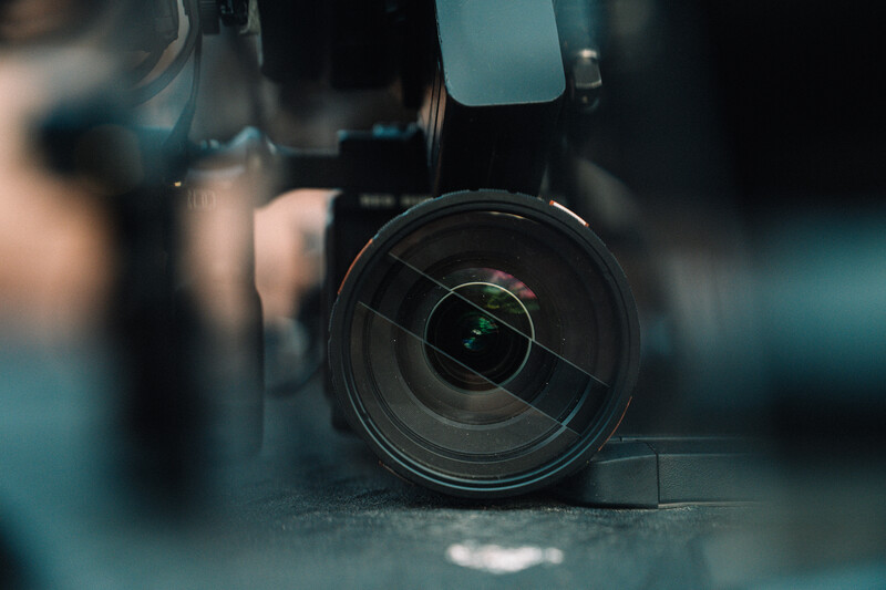 Camera lens in close-up with shallow depth of field and teal color grading.