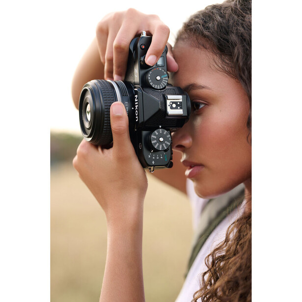 Photographer holding a vintage rangefinder camera up to their face in profile.