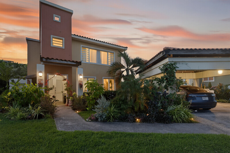 Modern residential home at dusk with warm interior lighting and landscaped front yard.