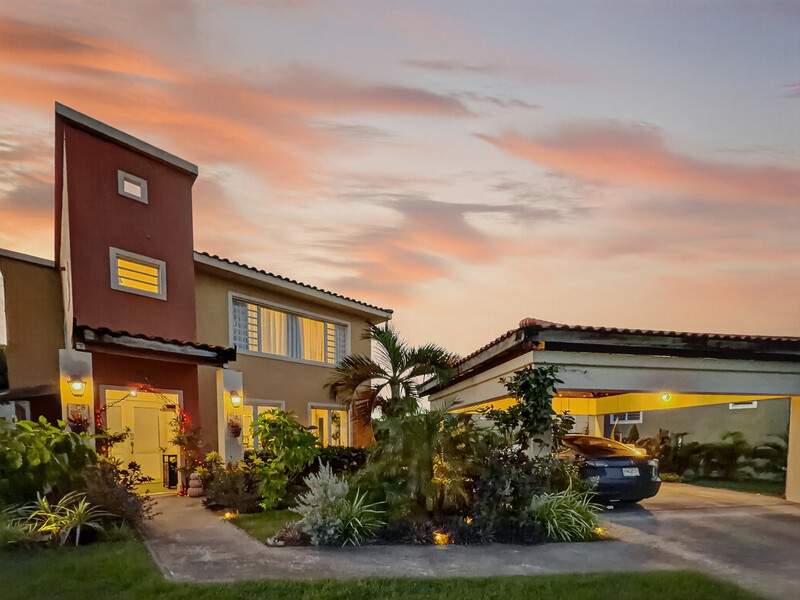 Modern residential home with burgundy accent wall illuminated at dusk under a colorful sunset sky.
