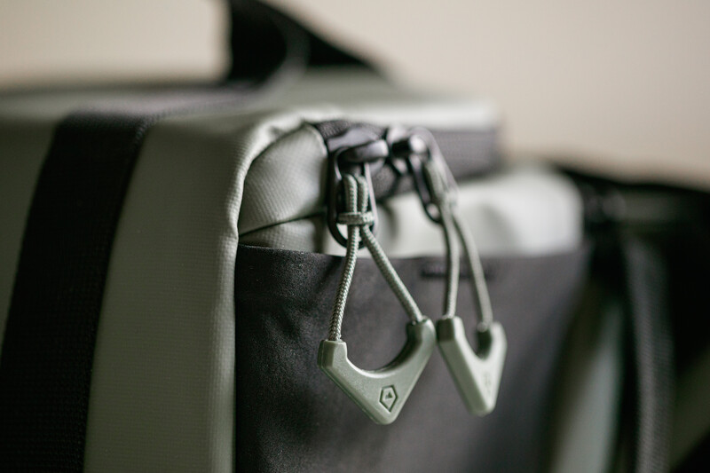 Close-up of carabiners clipped to the attachment point of a black and gray backpack strap.