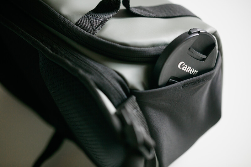 Canon camera lens cap stored in a black neoprene shoulder bag with gray trim.